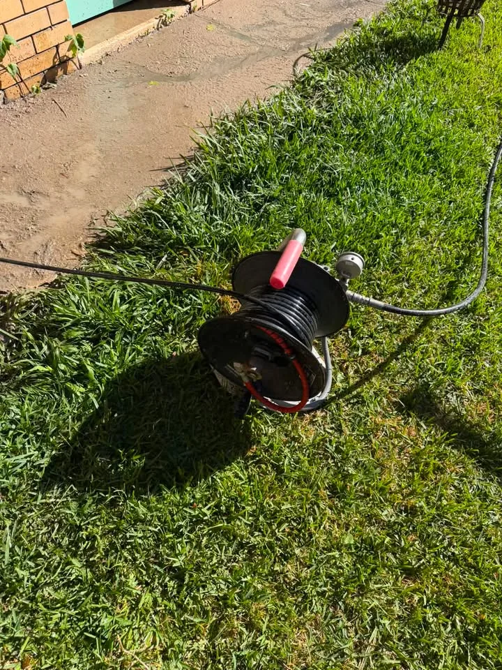 Jetting hose reel laid out on a lawn ready to clear a blocked drain