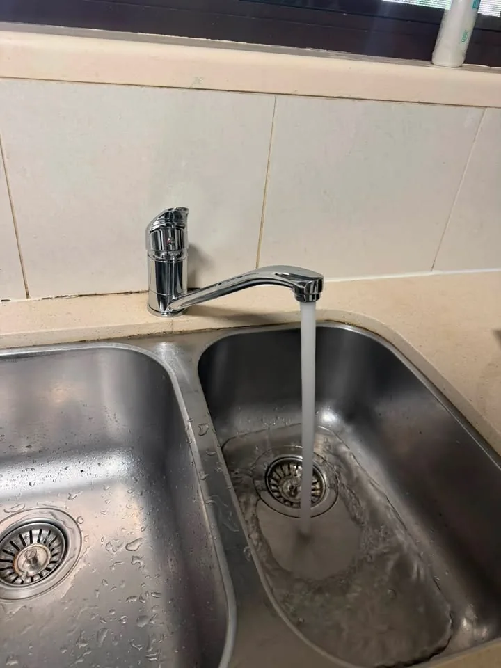 Kitchen mixer tap running into a stainless sink